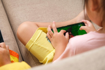 两个小女孩上瘾移动手机亚洲姐妹是<strong>玩游戏</strong>看漫画与他们的智能手机的沙发首页