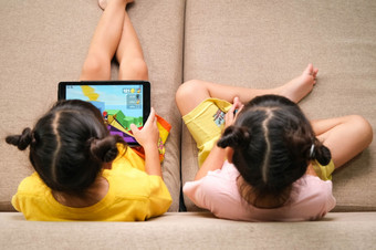 两个小女孩上瘾移动<strong>手机</strong>亚洲姐妹是玩游戏看漫画与他们的智能<strong>手机</strong>的沙发<strong>首页</strong>