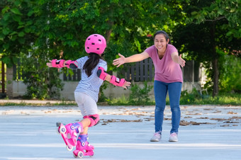 亚洲妈妈。帮助女儿<strong>实践</strong>辊滑冰的公园令人兴奋的<strong>户外</strong>活动为孩子们