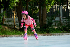 可爱的亚洲小女孩保护垫和安全头盔练习辊滑冰的公园令人兴奋的户外活动为孩子们