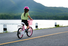 可爱的小女孩头盔骑自行车沥青路夏天快乐小女孩骑自行车在户外健康的夏天活动为孩子们