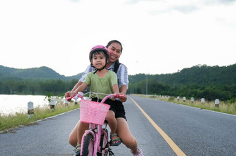 可爱的小女孩骑自行车与她的妈妈。湖路<strong>日</strong>落快乐<strong>家庭</strong>做户外<strong>活动</strong>在一起健康的夏天<strong>活动</strong>为孩子们