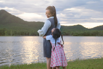 可爱的微笑小女孩拥<strong>抱</strong>她的<strong>妈妈</strong>。从后面有有趣的在一起的湖快乐家庭<strong>妈妈</strong>。和小女儿玩感觉快乐的公园