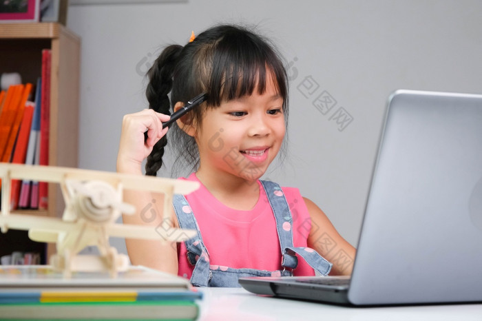 微笑小亚洲女孩研究在线有视频调用遥远的类与老师使用移动PC快乐女孩学习英语在线与移动PC首页在家教育概念