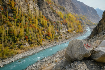 绿松石蓝色的水河流动通过喀拉昆仑山脉山范围沿着喀拉昆仑山脉高速公路和色彩斑斓的树叶树秋天季节hunza谷吉尔吉特巴尔蒂斯坦巴基斯坦