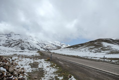 空铺路包围雪封顶山与多云的天空的高阿特拉斯范围摩洛哥