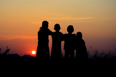 黑色的轮廓四个孩子们站在一起在那里天空日落背景