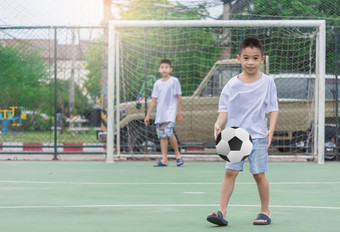 孩子们是穿拖鞋玩足球与模糊背景显示运动到锻炼后学校