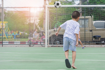 孩子们是穿拖鞋玩足球与模糊背景显示运动到锻炼后学校