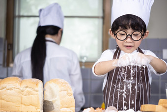 亚洲男孩穿眼镜烹饪与白色面粉揉捏面包面团教孩子们实践烘焙成分面包蛋餐具厨房生活方式快乐学习生活与家庭有趣的学习