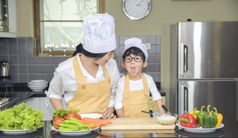 亚洲女人年轻的<strong>妈妈</strong>。与儿子男孩烹饪沙拉食物与蔬菜持有西红柿和胡萝卜贝尔<strong>辣</strong>椒板为快乐家庭烹饪食物享受生活方式厨房首页