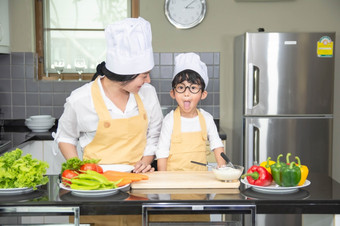 亚洲女人年轻的<strong>妈妈</strong>。与儿子男孩烹饪沙拉食物与蔬菜持有西红柿和胡萝卜贝尔<strong>辣</strong>椒板为快乐家庭烹饪食物享受生活方式厨房首页