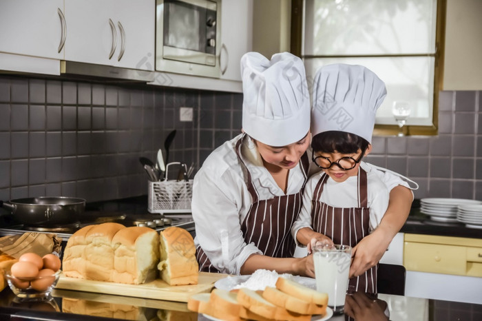 亚洲妈妈。和的儿子烹饪白色面粉揉捏面包面团母茶孩子们实践烘焙成分面包蛋餐具厨房生活方式快乐学习生活家庭有趣的学习