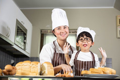 亚洲妈妈。和的儿子烹饪白色面粉揉捏面包面团母茶孩子们实践烘焙成分面包蛋餐具厨房生活方式快乐学习生活家庭有趣的学习