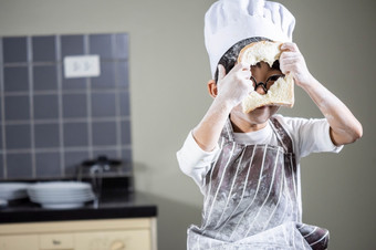 亚洲男孩穿眼镜烹饪与白色面粉揉捏面包面团教孩子们实践烘焙成分面包蛋餐具厨房生活方式快乐学习生活与家庭有趣的学习
