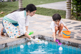 亚洲女人年轻的妈妈。和男孩儿子孩子们玩池玩具在游泳池边快乐学习生活与家庭有趣的学习和玩
