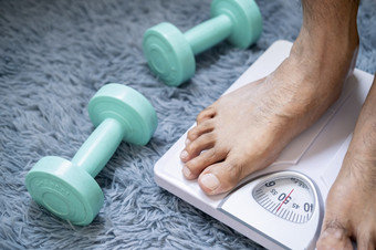 亚洲人脚男人。与身体重量尺度为测量重量损失重规模健康的减肥概念