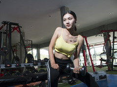 年轻的体育亚洲女人做练习与哑铃的健身房fitnesshealthy概念