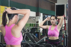 有吸引力的女看她的反射镜子健身房