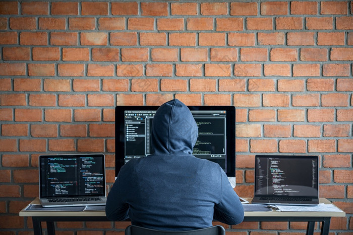 电脑黑客网络攻击概念危险的连帽黑客使用多个电脑打字坏数据成在线系统的访问与病毒感染偷信息