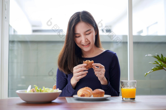 年轻的亚洲女人持有和有位吃面包与玻璃新鲜的橙色汁后吃健康的沙拉早餐健康生活方式首页