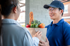 女人客户站的房子接受杂货店袋食物水果蔬菜从亚洲交付男人。蓝色的统一的那服务交付在冠状病毒新冠病毒流感大流行