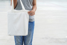赶时髦的人女人持有白色手提包袋为模拟空白模板