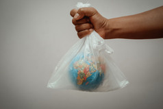 手持有全球塑料袋灰色的背景概念地球一天