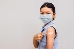肖像年轻的女指出石膏手臂后得到疫苗站白色背景