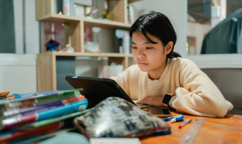 亚洲女孩学生学习在线电脑平板电脑在室内桌子上首页