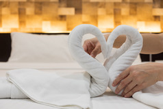 特写镜头手把折叠天鹅鸟新鲜的白色浴毛巾的床上表的酒店