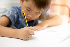 亚洲男孩做家庭作业和写作与的目的脸装修的橙色光焦点的孩子