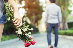 女人站与红色的玫瑰手悲伤爱结束打破的关系模糊男人。回来一边走走了离别公共公园户外破碎的心情人节一天概念