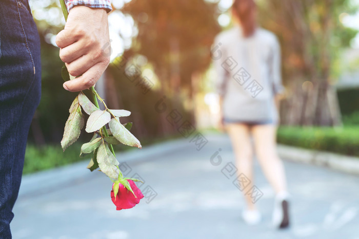 年轻的男人。站与红色的玫瑰手悲伤爱结束打破的关系模糊女人回来一边走走了离别公共公园户外破碎的心情人节一天概念