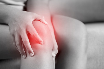 女人痛苦从感觉膝盖疼痛坐着沙发首页手按摩他的痛苦的膝盖健康哪和医疗概念