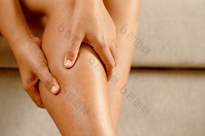女人痛苦从感觉膝盖疼痛坐着沙发首页手按摩他的痛苦的膝盖健康哪和医疗概念