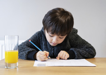 肖像可爱的孩子坐着独自一人做家庭作业与快乐脸可爱的孩子男孩使用铅笔写作白色纸学生做拼写测试<strong>homehome</strong>schooling概念