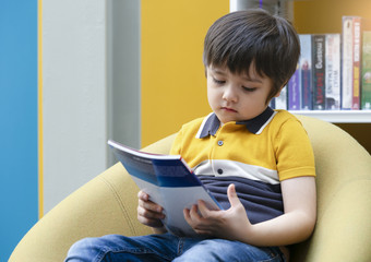 肖像不开心孩子坐着独自一人看的书与无聊脸图书馆心烦意乱智利男孩与伤心脸与深通过坐着独自一人书商店小男孩与无聊脸