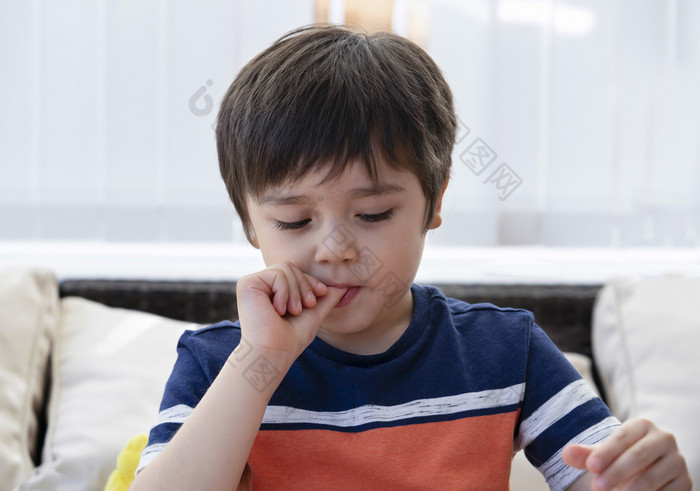高关键光可爱的男孩咬手指和看下来快乐孩子把手指他的口与好奇的脸而看卡通平板电脑