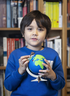 肖像年轻的孩子快乐脸持有全球坐着图书馆孩子男孩学习关于地理位置教育和在家教育概念