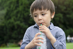 渴了男孩喝清洁水高加索人蹒跚学步的男孩持有瓶水健康的孩子与新鲜的脸后喝水而走的公园世界水一天孩子们健康哪概念