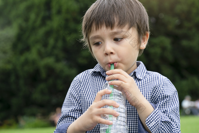 渴了男孩喝清洁水高加索人蹒跚学步的男孩持有瓶水健康的孩子与新鲜的脸后喝水而走的公园世界水一天孩子们健康哪概念