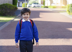 肖像快乐孩子男孩携带背包走的路的早....欣然学校孩子与微笑脸和兴奋回来学校教育概念