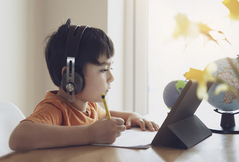 学前教育孩子使用平板电脑为他的家庭作业孩子穿头电话做家庭作业使用数字平板电脑搜索信息互联网首页学校教育教育概念社会距离