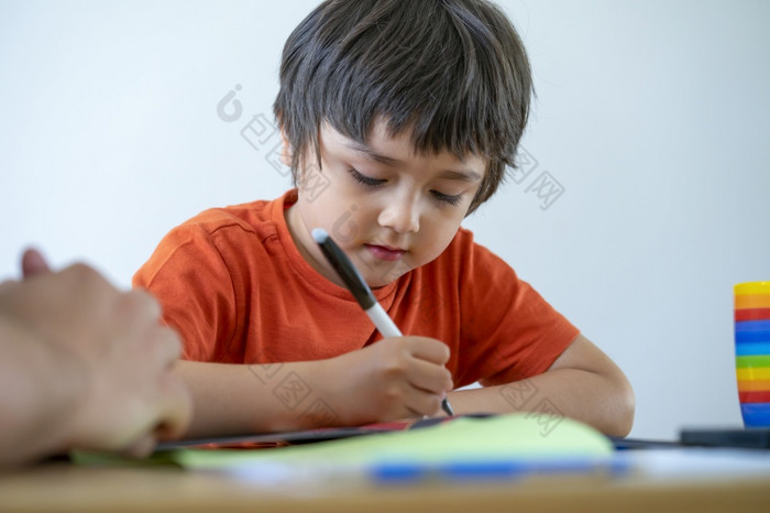 裁剪拍摄小男孩使用笔写作爸爸帮助他的儿子为他的家庭作业老师教学小男孩如何写在家教育概念