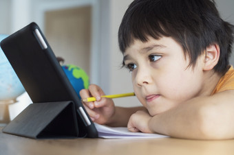新正常的生活孩子使用平板电脑学习首页孩子男孩严重的脸研究搜索的的想法从互联网为家庭作业首页学校教育距离学习电子学习在线教育