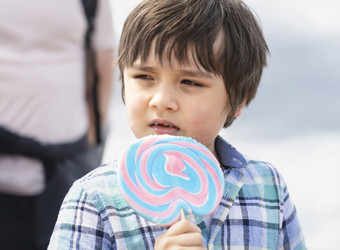 可爱的孩子吃棒棒糖快乐小男孩持有大糖糖果孩子与微笑脸吃糖果活跃的童年享受欢乐时光户外阳光明媚的一天夏天