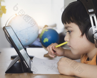 裁剪拍摄孩子使用平板电脑为他的家庭作业孩子使用数字平板电脑搜索信息互联网在<strong>首页</strong>学校<strong>教育</strong>社会距离电子学习在线<strong>教育</strong>