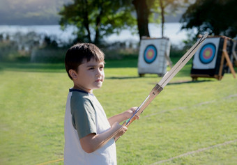 肖像年轻的孩子练习他的射箭混合比赛孩子做在户外活动夏天营冒险学校男孩拍摄弓与射箭培训体育运动学校