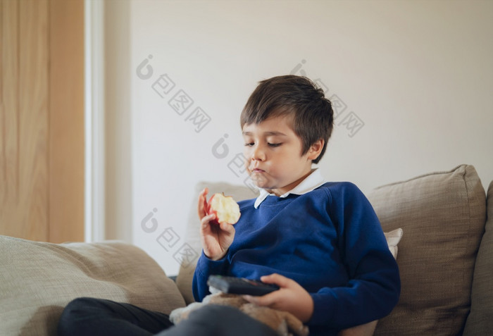 健康的学校孩子吃红色的苹果而看肖像孩子吃新鲜的水果为早餐快乐男孩坐着沙发放松贝福学校